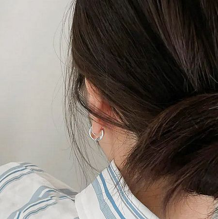 Model showcasing the versatile style of the small silver hoop earrings.