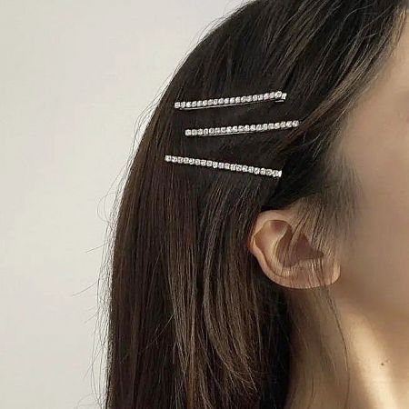 A model's hair styled with three elegant silver rhinestone hair clips, demonstrating a chic look.
