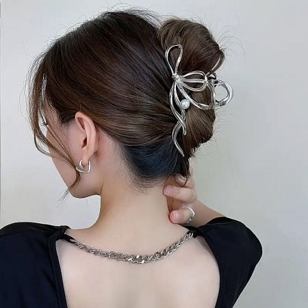 A model wearing the silver bow hair clip, paired with elegant jewelry.