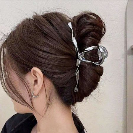 A woman with her hair styled in a bun, secured by a large silver metal hair clamp clip.