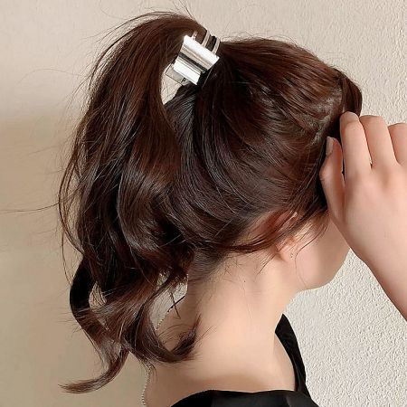 A model showcasing a sleek silver metal hair clip securing her ponytail.