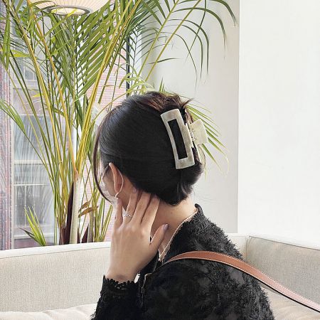 A woman wearing a white marbled acetate hair clip, demonstrating its elegant look.