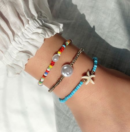 3Pcs/set Bohemian Colorful Seed Bead Bracelet - A model's wrist adorned with the 3-piece set of Bohemian Colorful Seed Bead Bracelets, style JRH-044, showcasing vibrant colors and gold-plated details.