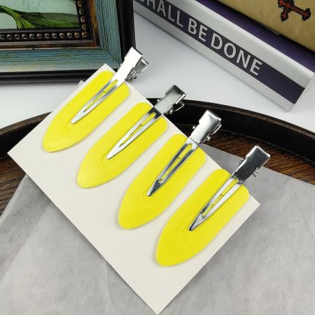 Close-up of a set of four yellow creaseless hair clips with silver clasps.