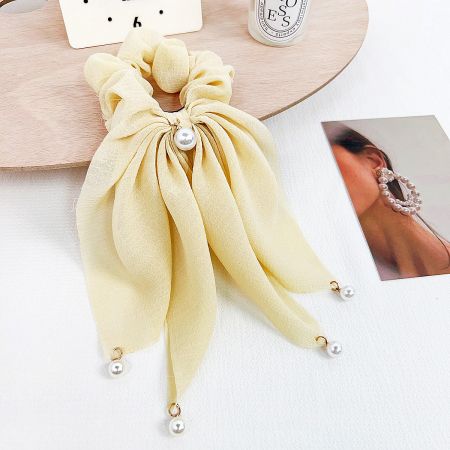 A vibrant yellow hair scrunchie featuring a delicate pearl embellishment.