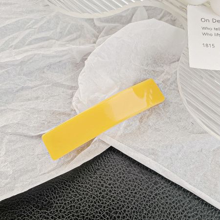 Close-up of a yellow acetic acid rectangle hair clip on a white background.