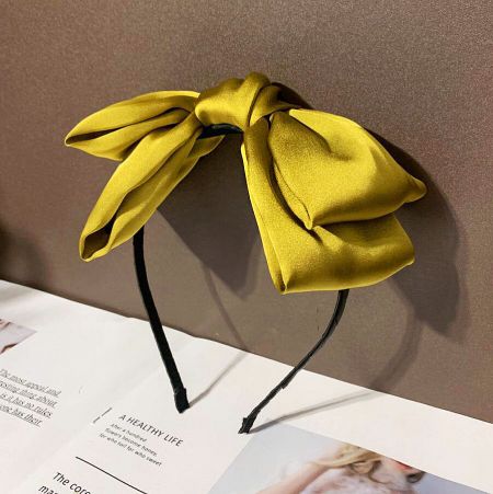 A bright yellow silk headband with a large, stylish bow.