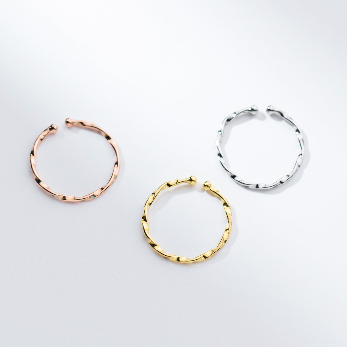 A set of three resizable 925 sterling silver twist style stackable rings in silver, gold, and rose gold finishes.