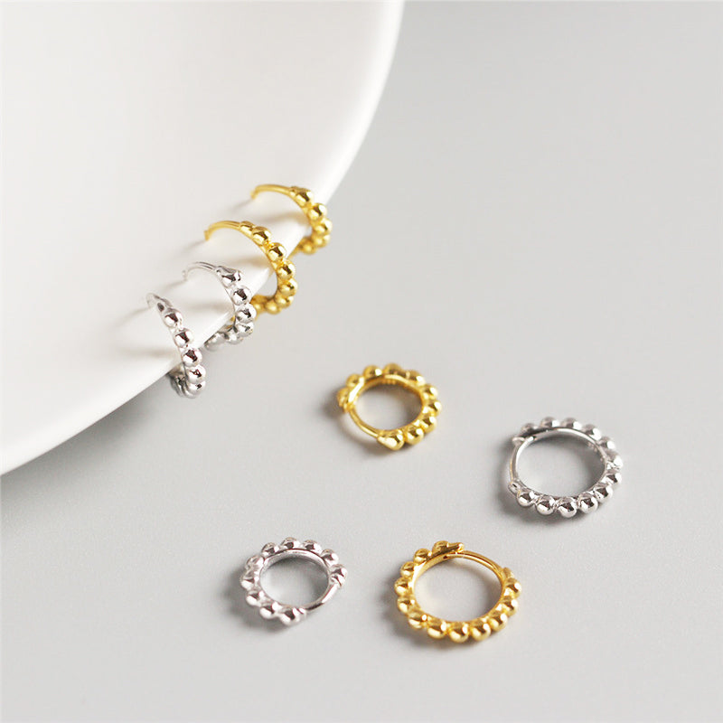 A pair of 925 sterling silver round bead hoop earrings shown in both polished gold and silver finishes, highlighting their classic design.