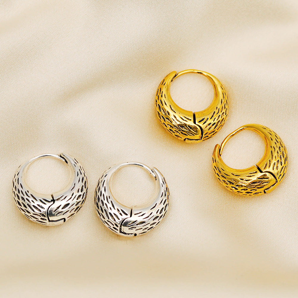 A pair of gold and a pair of silver antique-style basket bag hoop earrings with a textured leaf pattern, displayed on a white background.