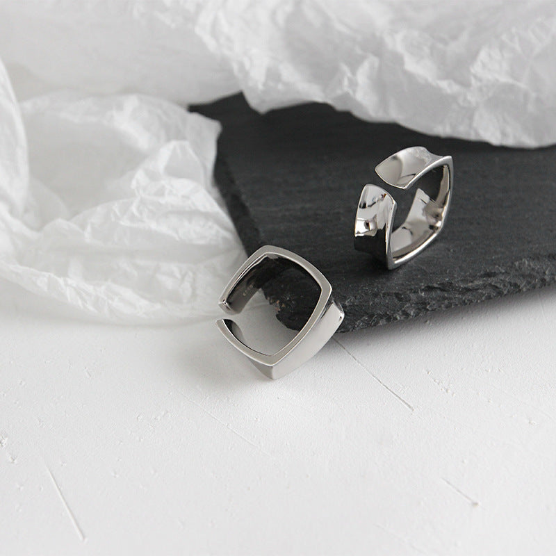 Two geometric open-band 925 sterling silver rings from a minimalist set, displayed on a textured surface, ideal for wholesale jewelry collections.
