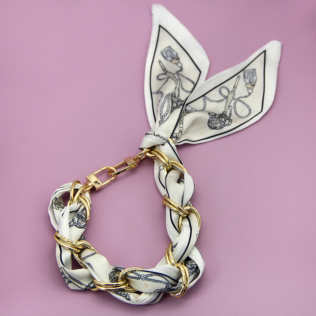 A stylish silk scarf phone strap with a nautical theme print, braided with gold-tone rings, shown on a white background.