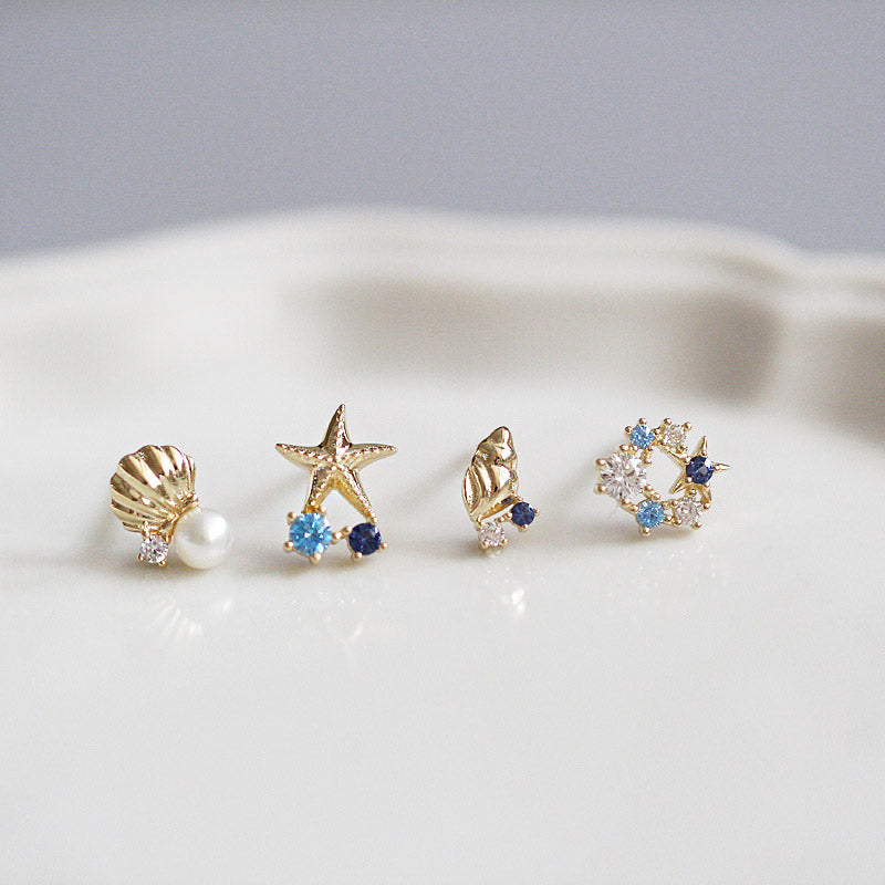 A collection of five pairs of 925 sterling silver ocean-themed stud earrings, including shell, scallop, and starfish designs with gemstone accents, displayed on a white background.