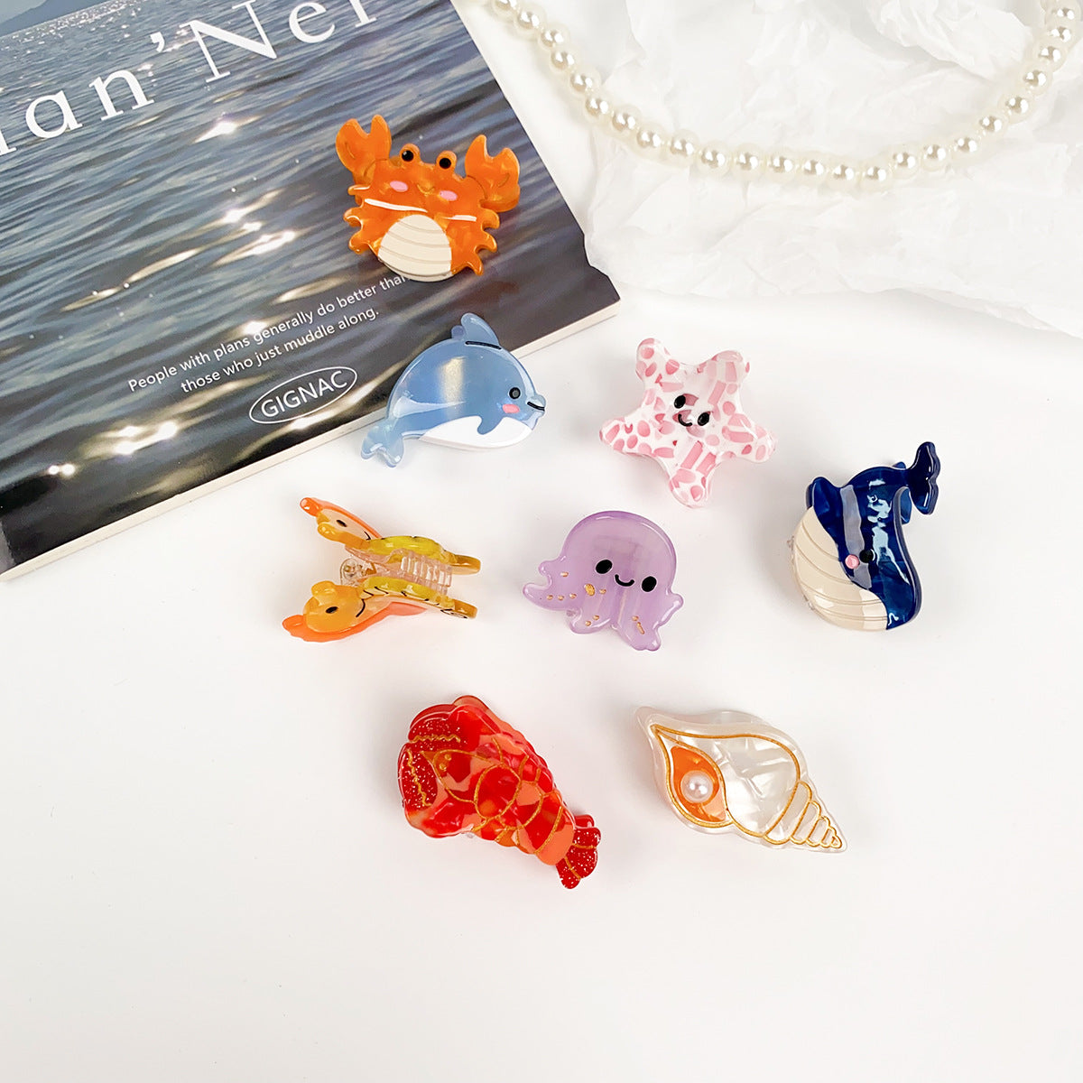 A vibrant collection of cute ocean-themed hair clips, including a dolphin, whale, and jellyfish, made from colorful acetate.