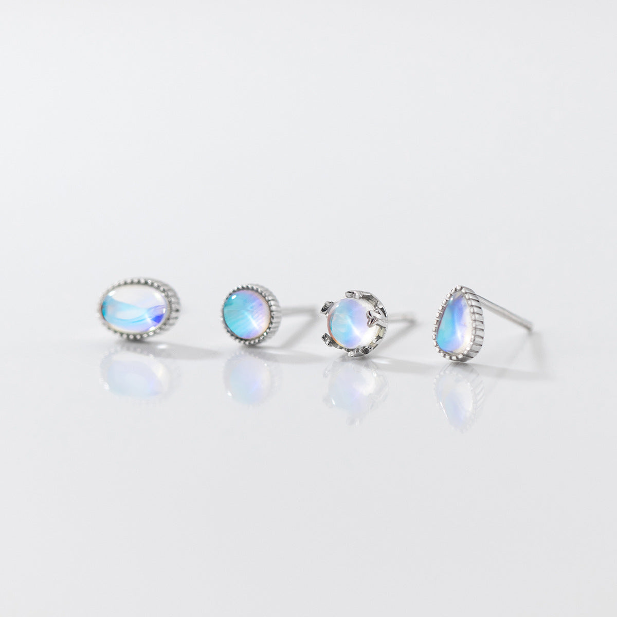 A collection of four pairs of 925 sterling silver stud earrings with iridescent moonstones, showcasing various elegant designs.