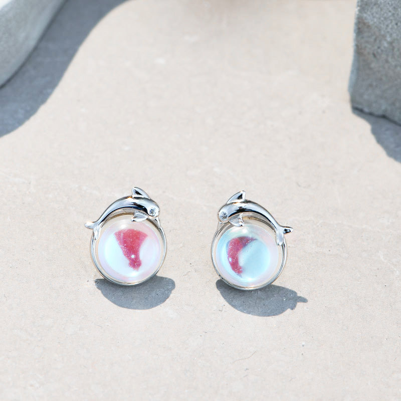 A close-up of the 925 sterling silver sea moonstone dolphin stud earrings, showcasing the detailed silver dolphin setting and the iridescent moonstone.