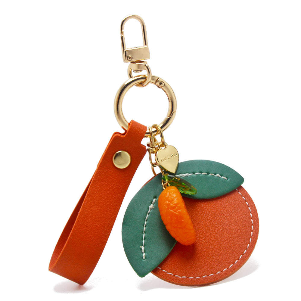 A vibrant orange-shaped PU leather keychain with a green leaf accent and gold metal clasp, part of a wholesale citrus fruit slice collection.