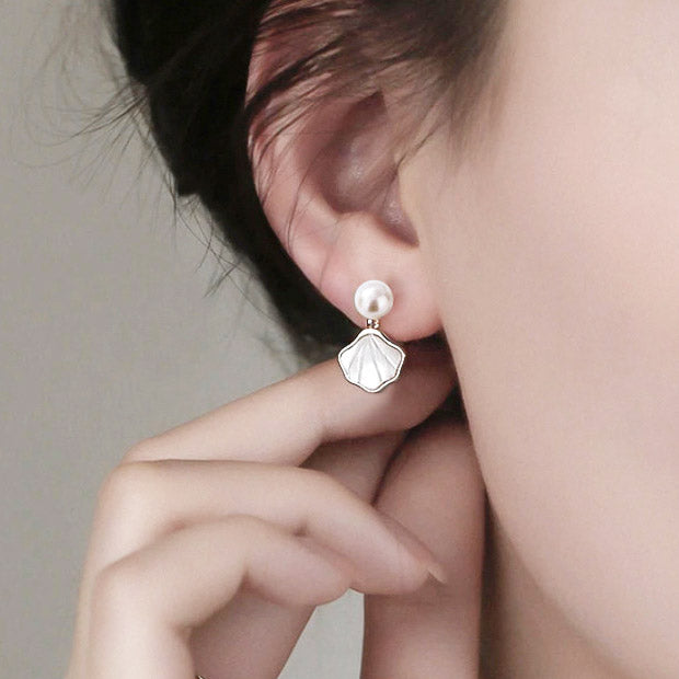 A woman modeling the elegant 925 sterling silver white shell and freshwater pearl drop earrings, showcasing their graceful design.