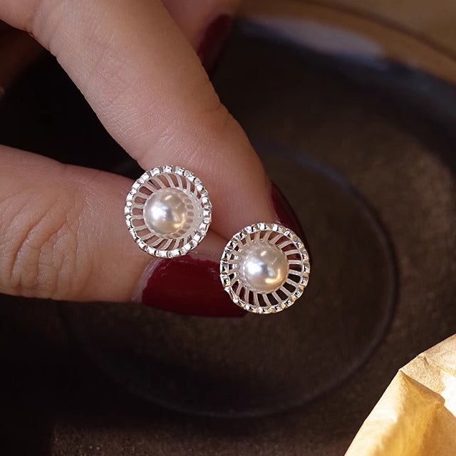 A close-up of the 925 Sterling Silver French Style Hollow Shell Pearl Stud Earrings, highlighting the intricate silver setting and central pearl.