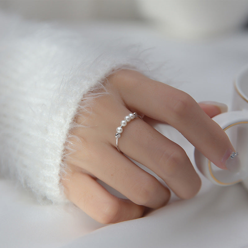 A close-up of a woman's hand wearing an adjustable 925 sterling silver ring with delicate pearl and silver bead accents.