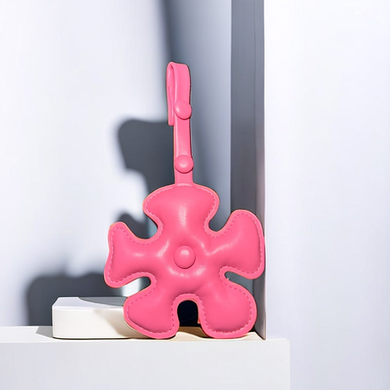 A close-up of a pink puzzle piece-shaped bag charm made from PU leather, attached to a handbag.