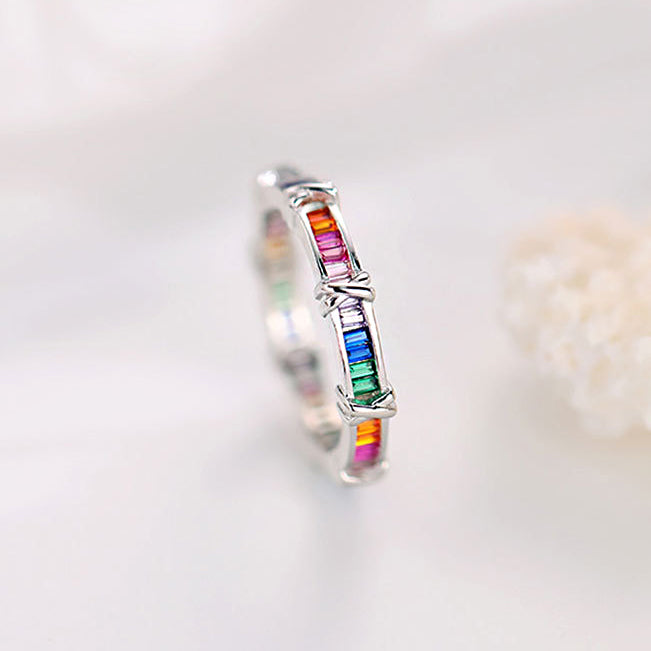 A close-up of a 925 sterling silver ring from the cross rainbow zircon set, showcasing the vibrant, multi-colored zircon stones inlaid in the band.