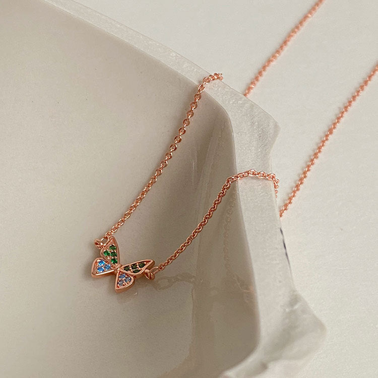 A delicate rose gold 925 sterling silver necklace featuring a butterfly pendant set with vibrant, multicolored zirconia stones, on a clean white background.