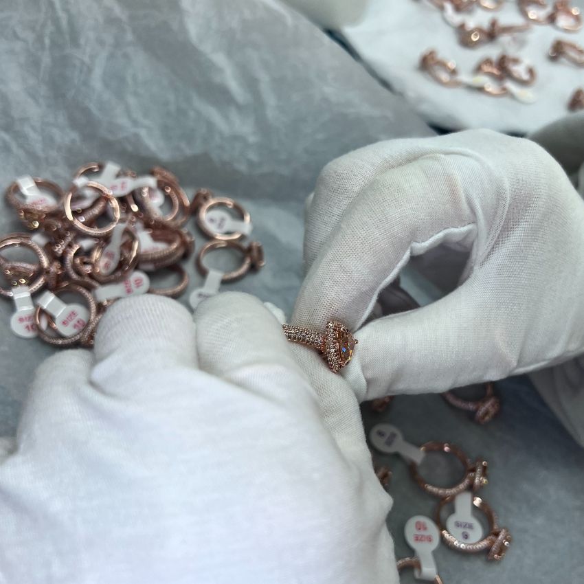 A detailed quality inspection of a custom rose gold ring with a large oval gemstone at the JR Fashion Accessories workshop.