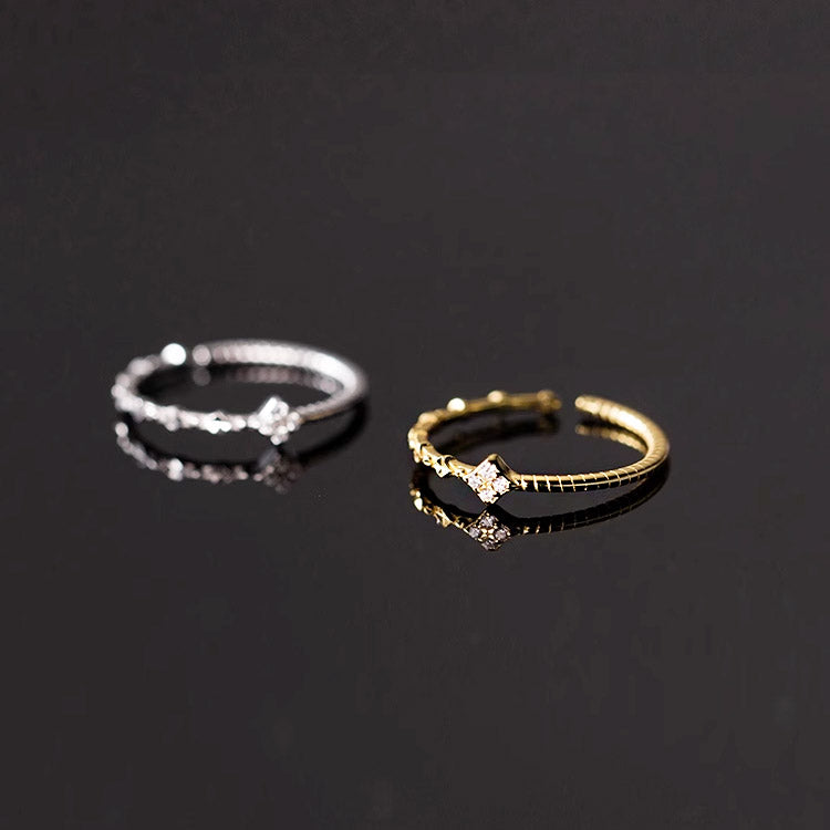 A set of two minimalist adjustable rings in 925 sterling silver and gold-plated finishes, each featuring a delicate twist design and sparkling cubic zirconia stones.