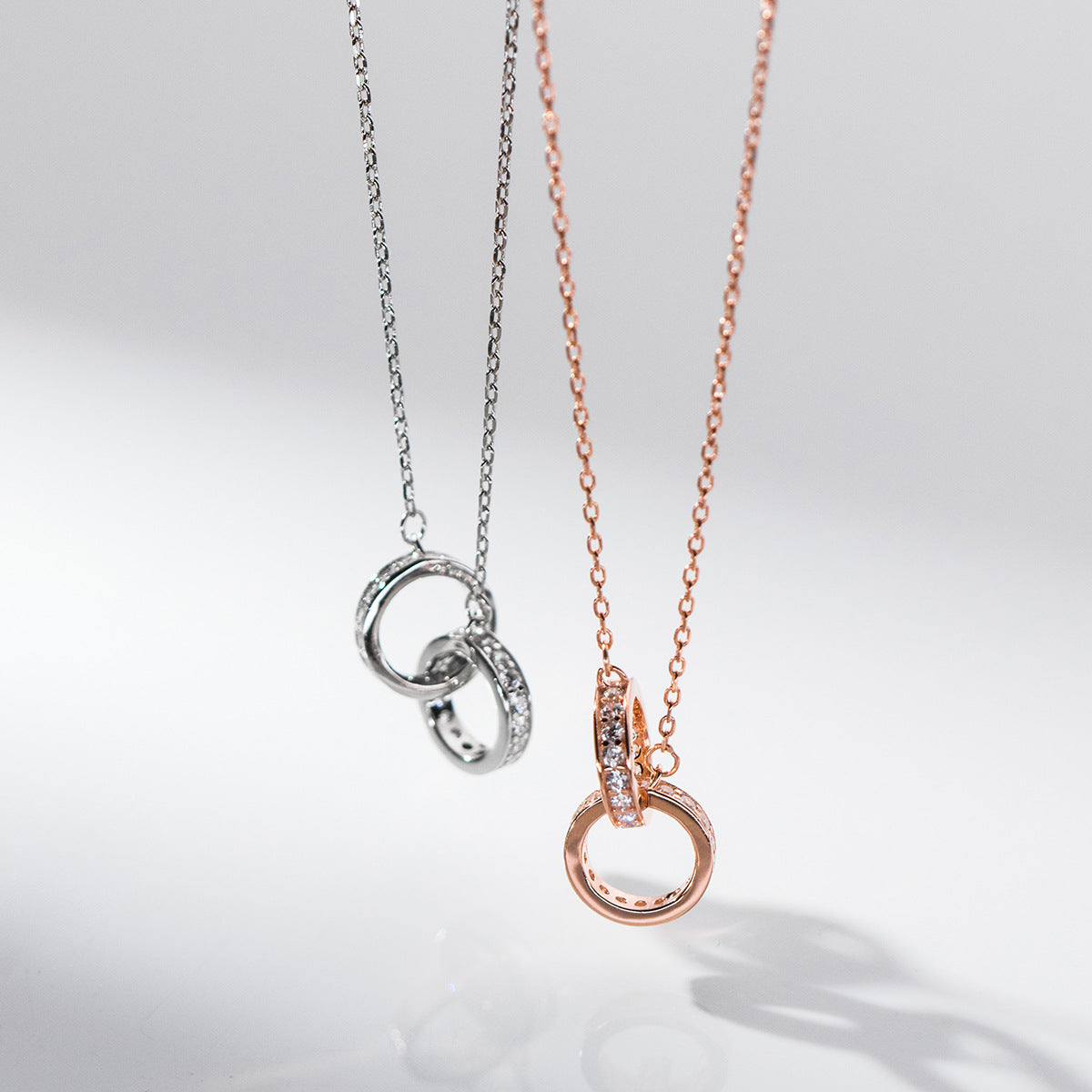 A set of 925 sterling silver and rose gold interlocking circle pendant necklaces with cubic zirconia accents, displayed on a white background.