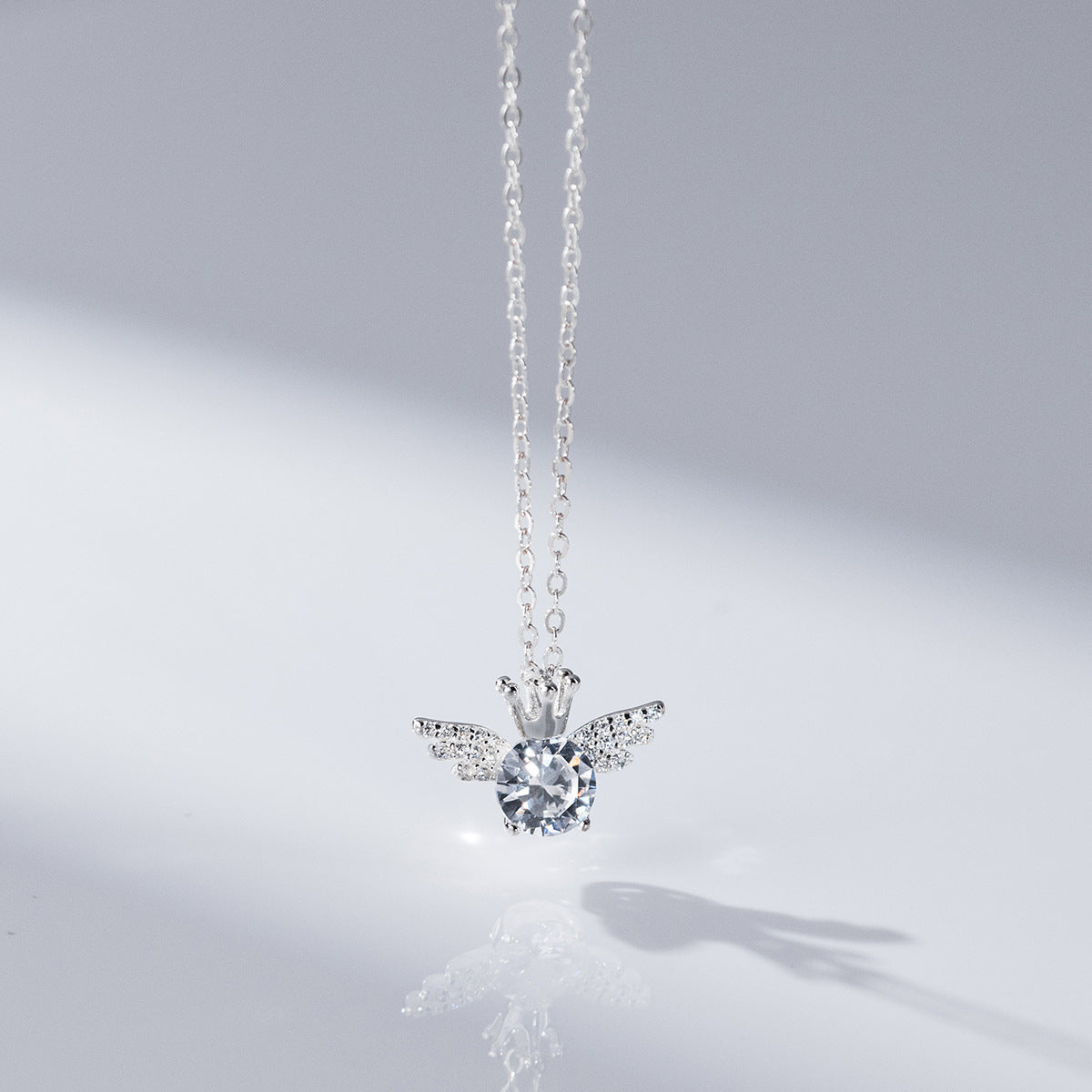 A detailed view of a 925 sterling silver crown-wing pendant necklace, showcasing its intricate angel wing design and sparkling clear gemstone.