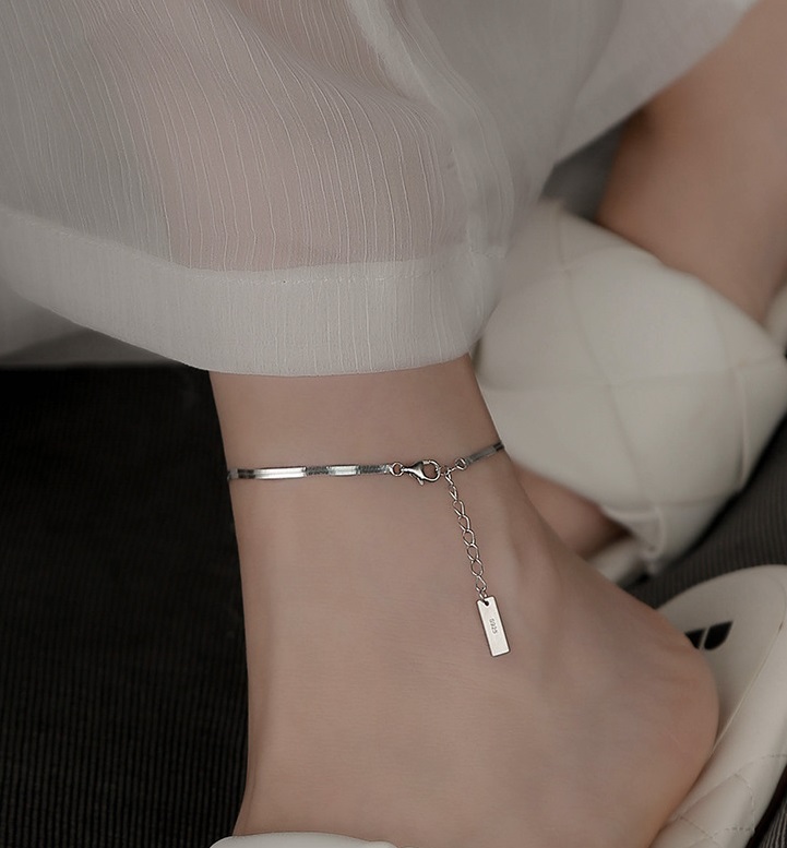 A model wearing the elegant 925 Sterling Silver Flat Snake Chain Anklet, highlighting its sleek design and fit.