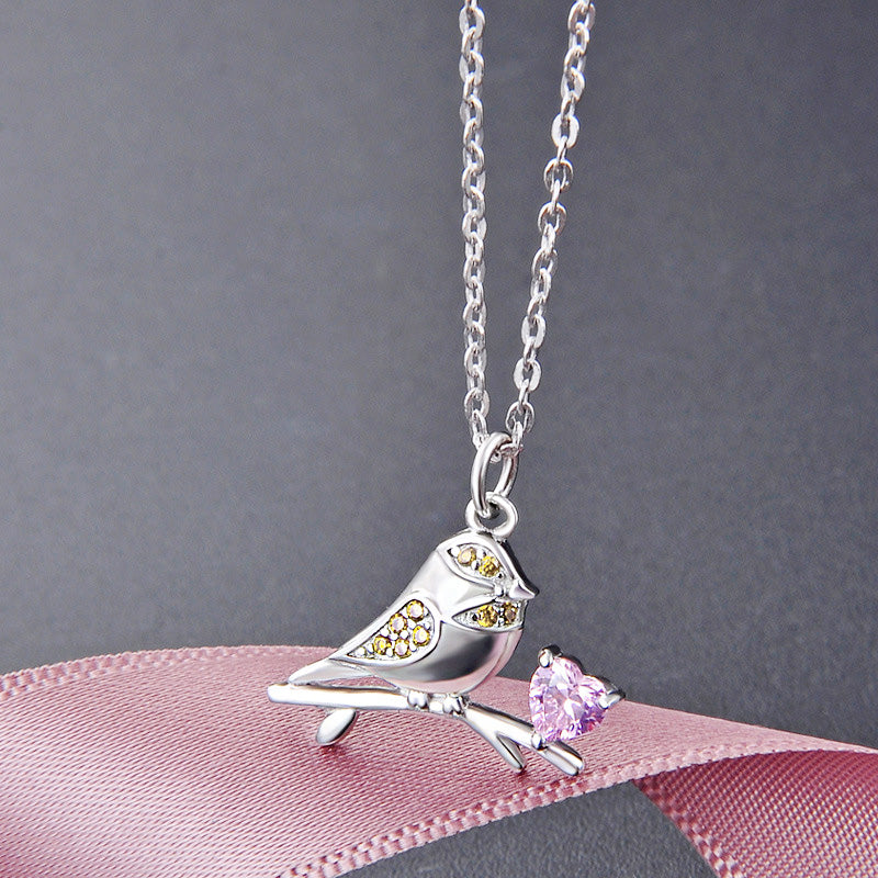 Close-up of a 925 sterling silver sparrow bird pendant necklace, detailed with a pink heart zircon and yellow gemstone accents.