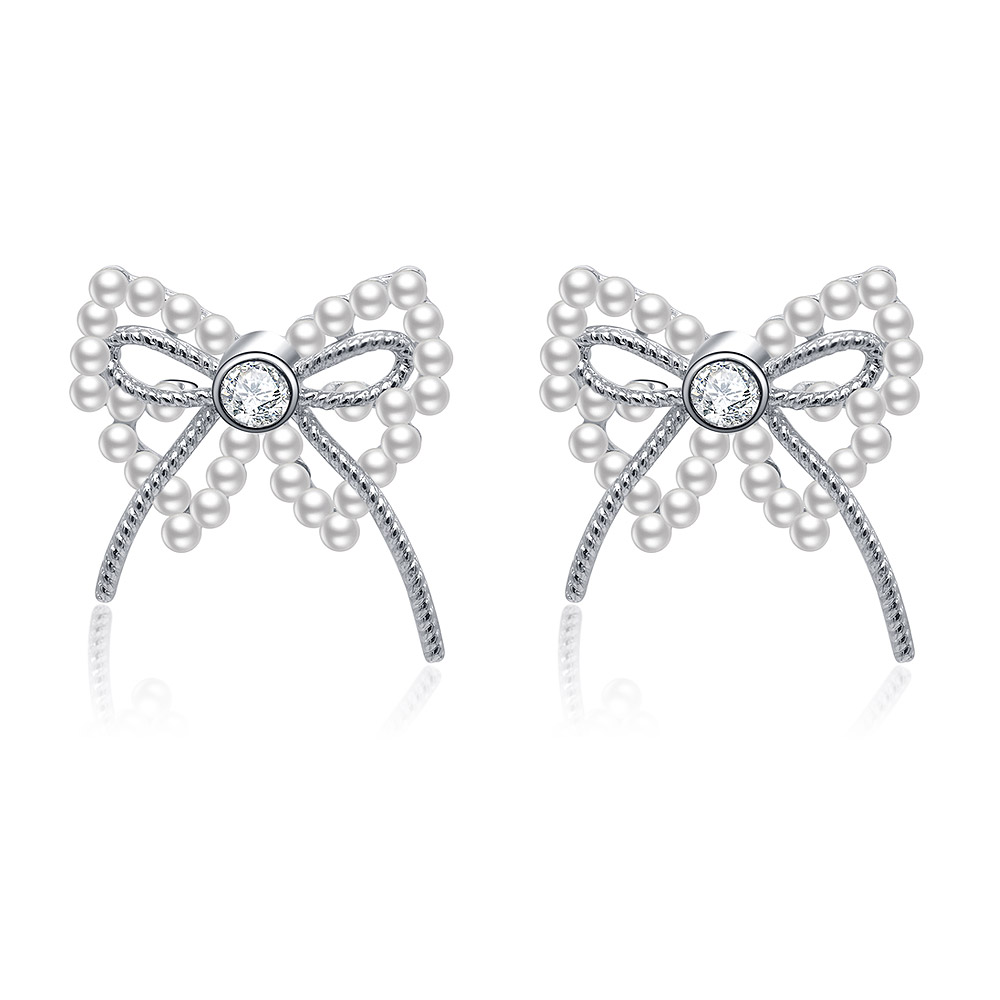 A pair of Pearl Ribbon Bow Pierced Earrings in rhodium-plated brass, showcasing the intricate bow design with a central white pearl and sparkling cubic zirconia accents.