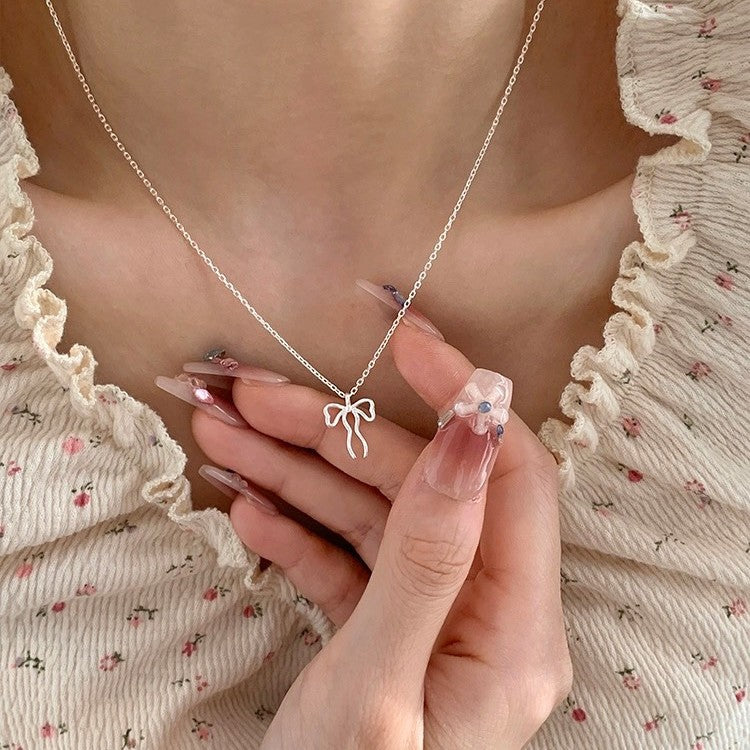 Close-up of a 925 sterling silver asymmetrical bow ribbon pendant on a delicate chain, showcasing its elegant and whimsical design.