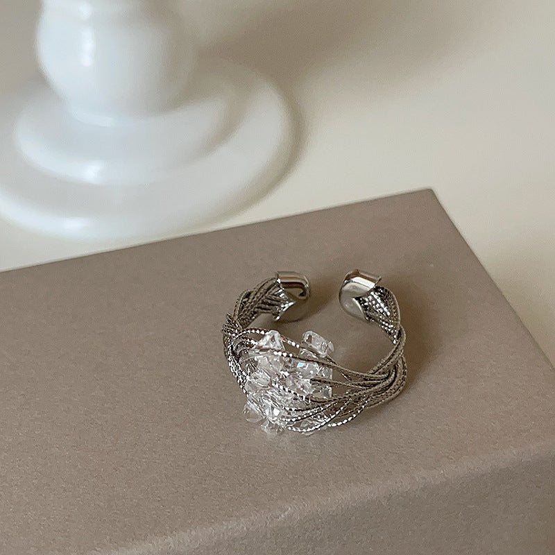 A silver-tone adjustable ring with an intricate wire-wrapped design and a sparkling crystal centerpiece, displayed on a neutral background.