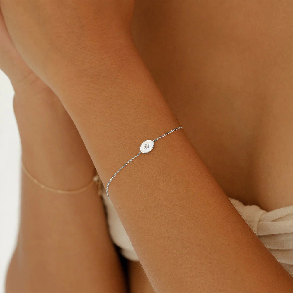 A delicate 925 sterling silver bracelet featuring a sparkling starburst charm with zircon, elegantly worn on a wrist.