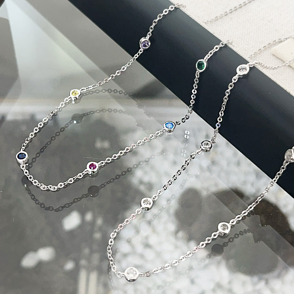 A collection of wholesale 925 sterling silver chain necklaces, each featuring a vibrant 4mm multicolored CZ stone charm, displayed elegantly.