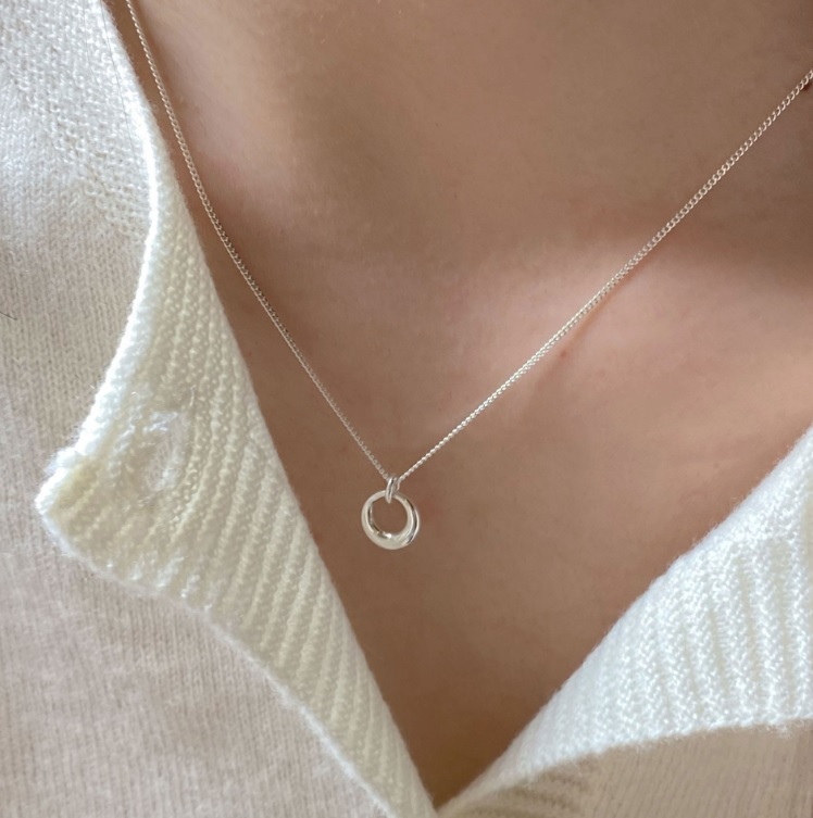 A model wearing the elegant 925 sterling silver circle pendant necklace, showcasing its delicate design against a white sweater.