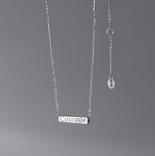 A close-up of a 925 sterling silver pendant necklace with the word 'Courage' engraved on a rectangular tag, showcasing the custom engraving option.