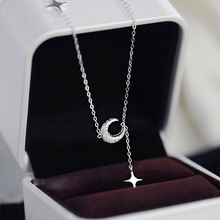 A delicate 925 sterling silver necklace with a crescent moon and star tassel pendant, elegantly displayed in a white jewelry box.
