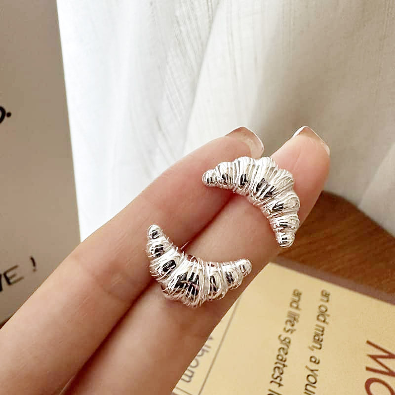 A pair of wholesale 925 sterling silver croissant-shaped stud earrings with a detailed, textured finish, displayed on a neutral background.