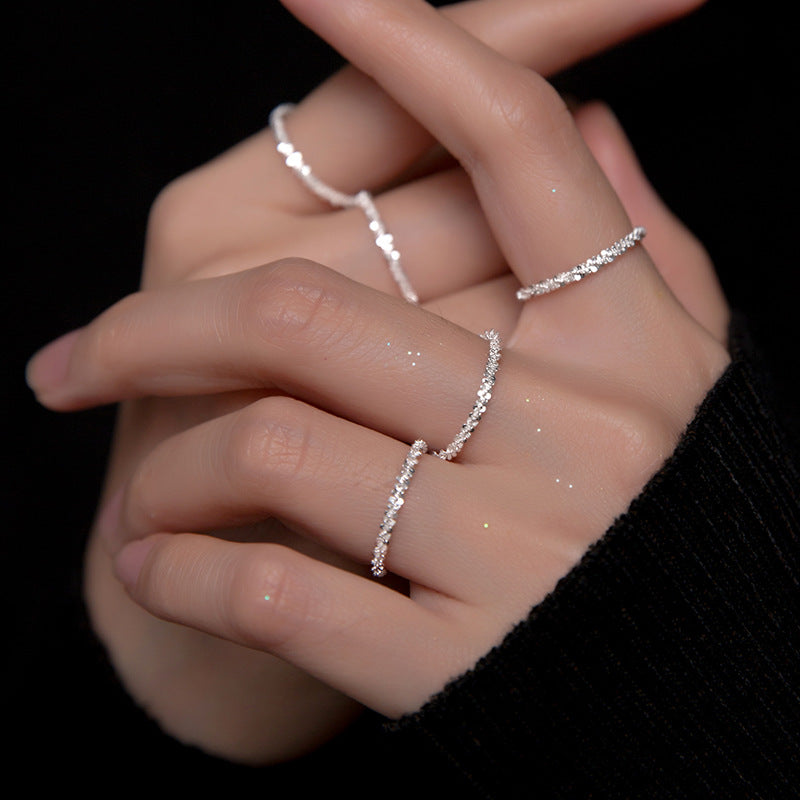 A model's hand showcasing a set of five sterling silver rings with sparkling gemstone accents, demonstrating how they can be stacked for a stylish look.
