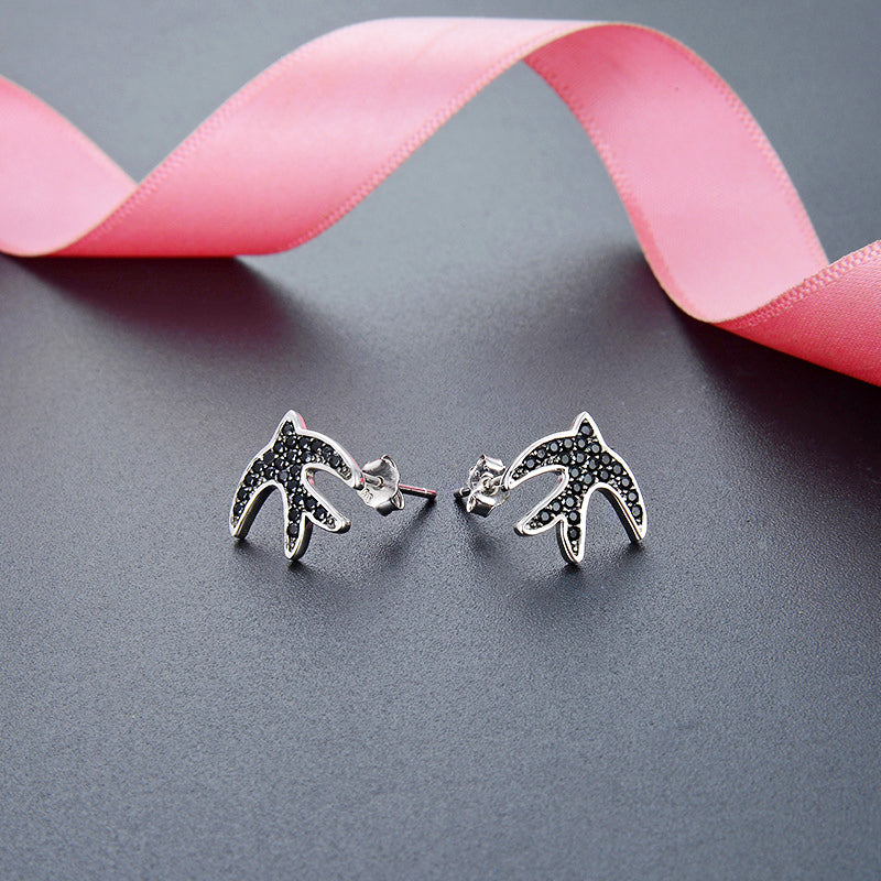 A pair of 925 sterling silver swallow bird stud earrings, intricately designed with sparkling black zircon stones, displayed on a white background.