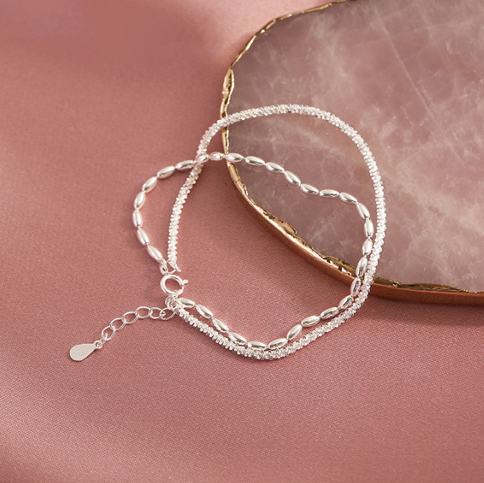 A close-up view of the 925 Sterling Silver Adjustable Double Layer Chain Bracelet, showcasing its delicate dual-chain design on a soft pink background.