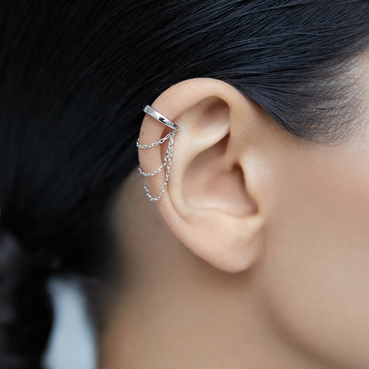 A close-up of a wholesale 925 sterling silver chain ear cuff earring with a clip-on, non-pierced design, displayed on a white background.