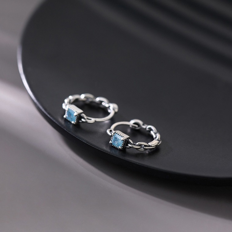 A pair of 925 sterling silver mint cube geometric stud earrings with sparkling blue cubic zirconia gemstones on a white background.