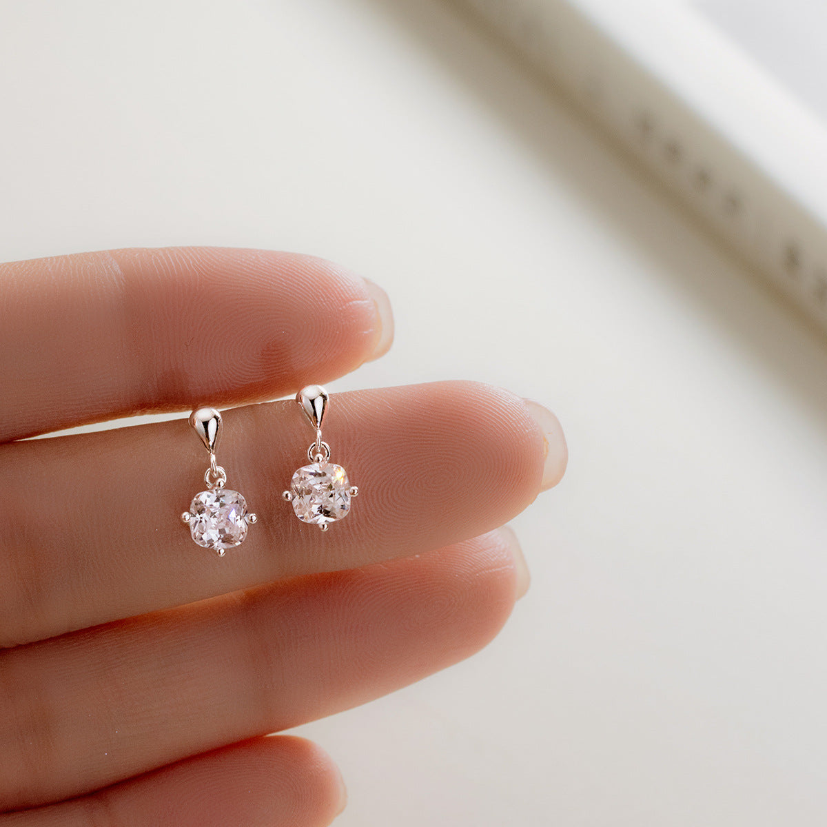 A pair of 925 sterling silver drop earrings featuring a single, sparkling cubic zirconia in a classic prong setting.