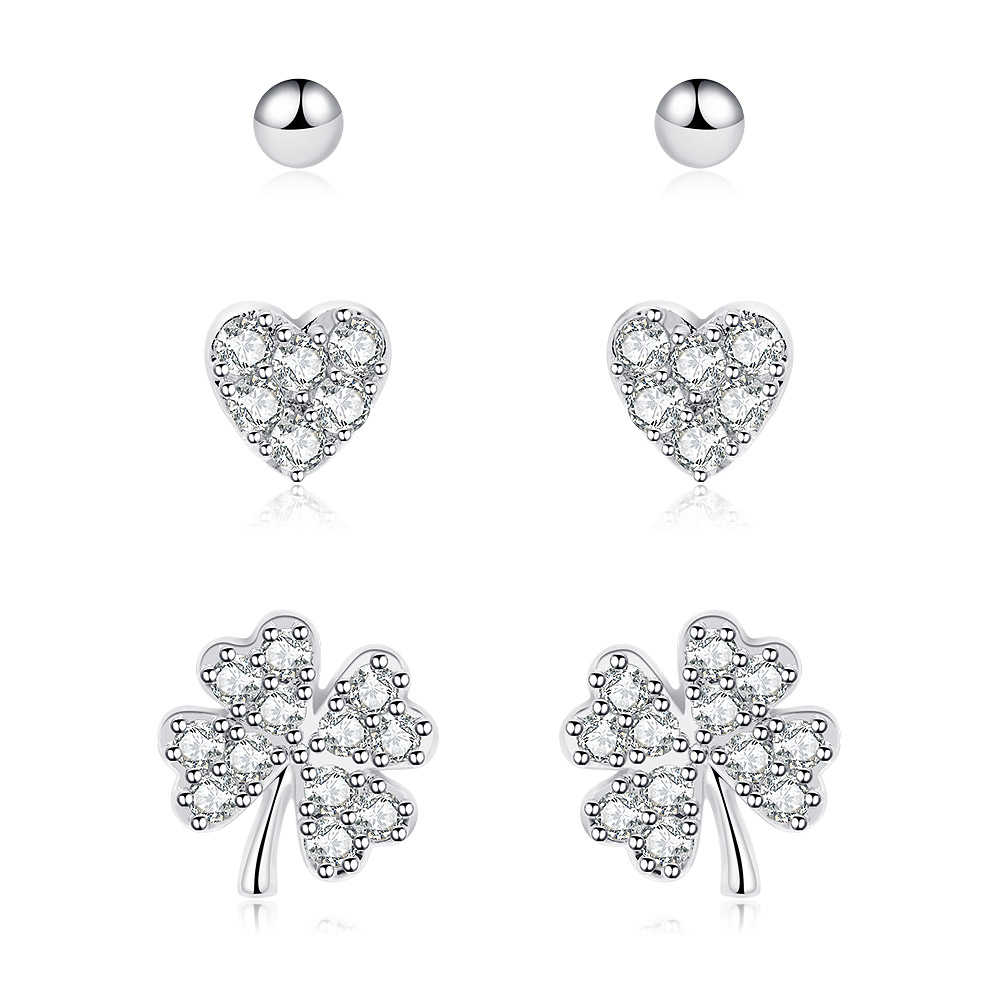 A set of three rhodium-plated stud earrings featuring a tiny heart, a ball bead, and a clover leaf, all with sparkling cubic zirconia accents.