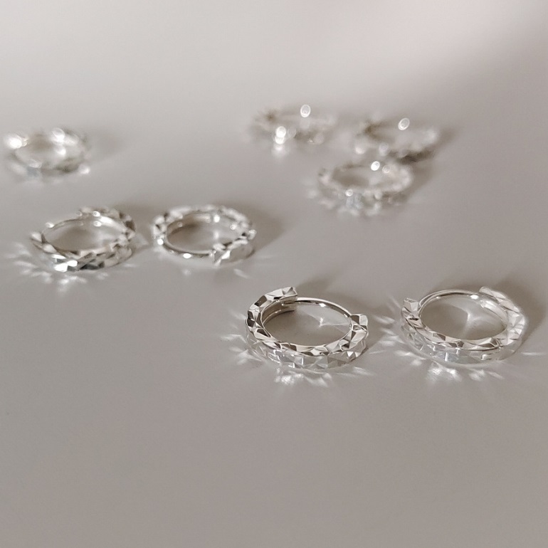 A pair of 925 Sterling Silver Diamond Cut Hook Earrings showcasing their intricate faceted texture on a white background.